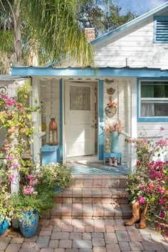 a white house with blue trim and flowers in front