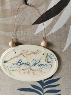 a white plate with flowers on it hanging from a hook in front of a wall