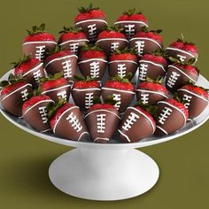 chocolate covered strawberries are arranged on a cake plate with footballs and strawberries