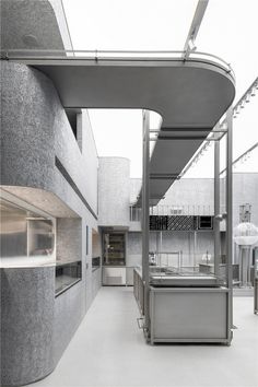 an empty kitchen with stainless steel appliances and counter tops on the outside wall, in front of a concrete building