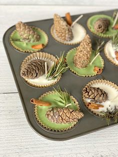 cupcakes decorated with pine cones and cinnamon sticks are sitting on a baking tray