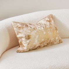 a white chair with a gold pillow on it