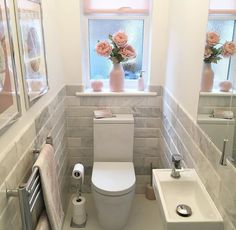 a white toilet sitting in a bathroom next to a sink and window with pink flowers