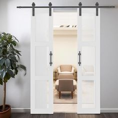 an open door leading to a living room with a chair and potted plant in the corner