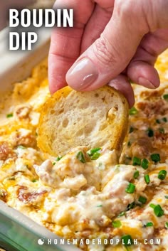 a hand dipping a piece of bread into a casserole with cheese and chives