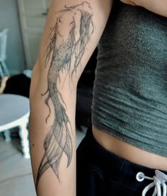 a woman's arm with a fish tattoo on the left side of her body