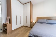 a bed sitting next to a white closet in a bedroom on top of a hard wood floor