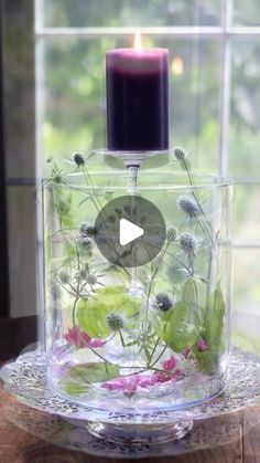 a candle that is sitting inside of a glass container with flowers in it and water