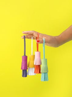 a person holding four colorful toothbrushes in their hand on a bright yellow background