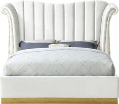 a white bed with an upholstered headboard and gold trimmings on it