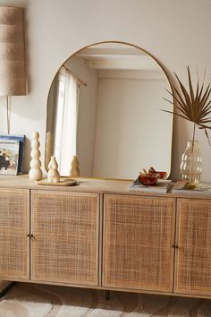 a large mirror sitting on top of a wooden dresser next to a vase with an air plant