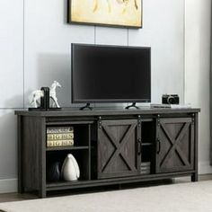 a flat screen tv sitting on top of a wooden entertainment center next to a window