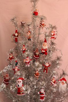 a silver tinsel christmas tree with santa claus ornaments