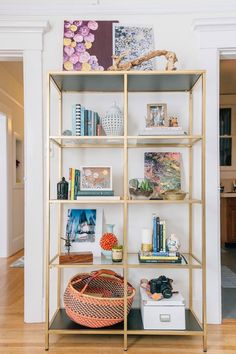 a book shelf filled with lots of books on top of a hard wood floor next to a white wall