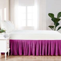 a white bed with purple pleated bedskirt