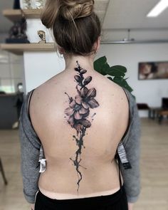 the back of a woman's neck with flowers tattooed on her upper and lower back