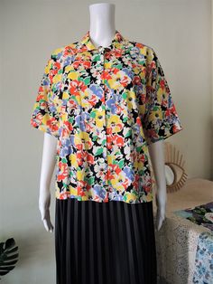 Beautiful Vintage short sleeve blouse from the 1980s. Comfortable cotton fabric with a vibrant summer floral pattern. Straight, boxy cut, wide sleeves, button down. Looks great with a pair of jeans and flatform sandals. BRAND: C&A ERA: 1980s COLOR: White, black, green, yellow, red, lilac FABRIC: 100% cotton SIZE: No size tag, fits best size M to small L (or S for a more oversized fit) - please check measurements below for reference MEASUREMENTS: Pit to pit 54cm, total length 60cm CONDITION: Multicolor Floral Print Short Sleeve Shirt For Spring, Collared Short Sleeve Floral Print Shirt For Spring, Retro Short Sleeve Shirt With Relaxed Fit For Spring, Retro Relaxed Fit Short Sleeve Shirt For Spring, Spring Short Sleeve Shirt With Floral Print, Retro Button-up Short Sleeve Shirt For Spring, Short Sleeve Shirt With Floral Print For Spring, Floral Print Short Sleeve Shirt For Spring, Summer Floral Print Short Sleeve Shirt