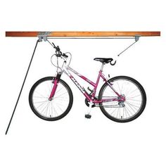 a pink bike is hanging from a wooden rail with two bars attached to the front