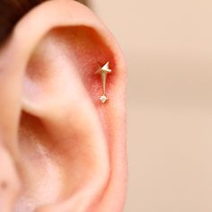 an ear with a single diamond in the middle and a tiny gold arrow on it