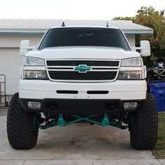 a white truck parked in front of a house with two large tires on the front