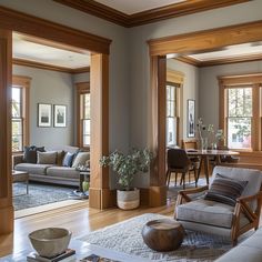 a living room filled with furniture and lots of wood trimming on the walls in front of windows