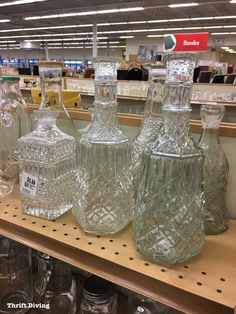 many glass jars are sitting on the shelf in a store with price signs above them