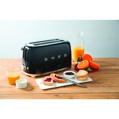 a toaster sitting on top of a wooden table next to oranges and juice