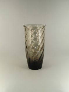 a black and white glass vase sitting on top of a gray table next to a wall