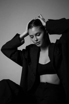 a woman sitting on the floor with her hands in her hair and wearing a jacket