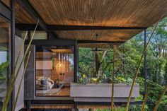 the inside of a modern house with plants and trees in the foreground, along with an outdoor deck