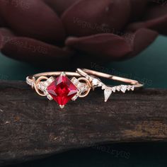 a close up of two rings on a piece of wood with a red stone in the middle