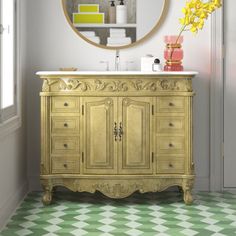 a bathroom with a gold vanity, mirror and yellow flowers in vases on the floor