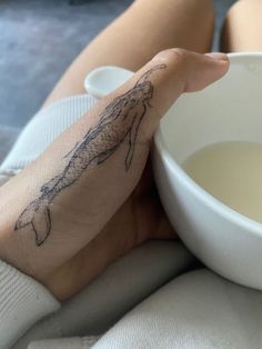 a person with a tattoo on their arm holding a white bowl