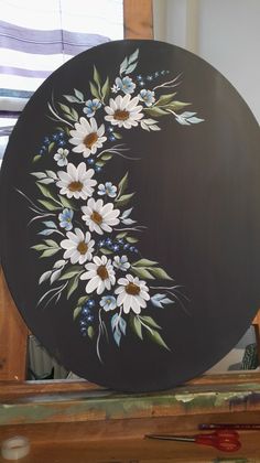 a black plate with white and blue flowers painted on it