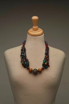 This antique Berber Moroccan necklace is a unique and beautiful piece of jewelry, crafted by skilled artisans in the Mid Atlas Mountains. The necklace features a stunning array of rainbow-colored beads, strung together with precision to create a mesmerizing and vibrant piece. The metal ball in the center serves as the centerpiece, adding a touch of shine and elegance to the already stunning necklace. This necklace is not just a work of art, it is also a meaningful piece of cultural heritage. The Artisan Multicolor Wooden Beaded Necklaces, Artisan Multicolor Wooden Beads Necklace, Traditional Multicolor Wooden Beaded Necklaces, Traditional Multicolor Wooden Beaded Necklace, Handmade Bohemian Turquoise Necklace With Oval Beads, Wooden Beads Amulet Jewelry For Festival, Artisan Multicolor Necklaces With Large Beads, Unique Multicolor Wooden Beads Necklaces, Artisan Multicolor Necklace With Large Beads