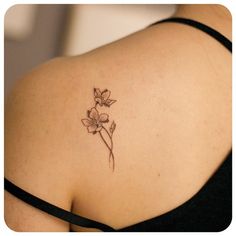 the back of a woman's shoulder with a small flower tattoo on her left arm