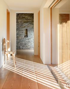 a wooden chair sitting on top of a hard wood floor next to a stone wall