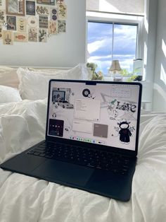 an open laptop computer sitting on top of a white bed covered in pillows and blankets