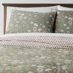 a bed with green and pink floral bedspread, pillows and pillowcases