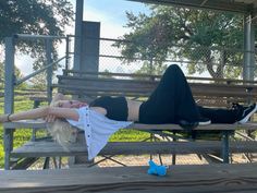 a woman laying on top of a wooden bench