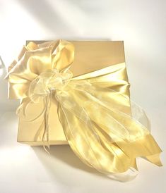 an open gift box with a bow on it's side, sitting on a white surface