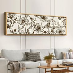 a living room with a white couch and wooden coffee table in front of a floral painting on the wall