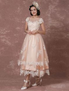 a woman wearing a dress with white flowers on it, posing in front of a wall