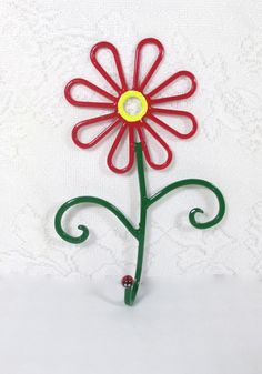 a red and green metal flower on a white background