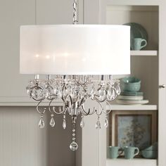 a white chandelier hanging from a ceiling in a room with shelves and dishes