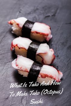 three sushi rolls with white and black strips on top of them, sitting on a slate surface