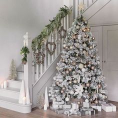 a decorated christmas tree sitting under a banister next to a stair case filled with presents