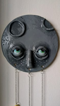 a clock with eyes and chains hanging from it's face on the wall,