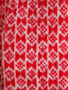 a red and white knitted blanket with hearts on the bottom, in close up