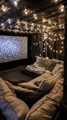 a large couch sitting in front of a projector screen with lights on the ceiling